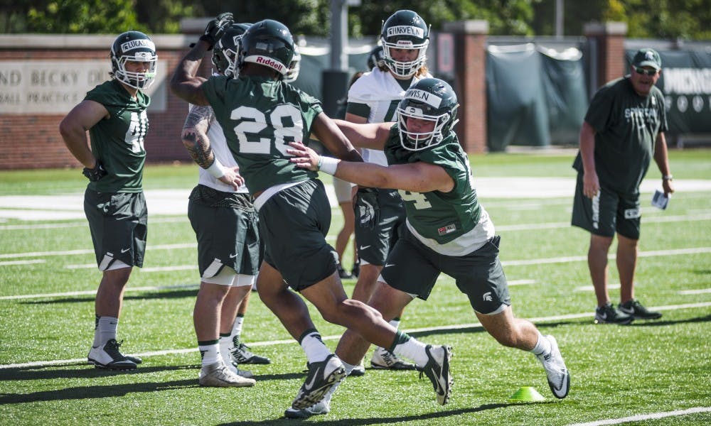 <p>Junior safety David Dowel (28), left, and redshirt tight end Noah Davis (84), right, perform a drill during the football practice on July 31, 2017, at the practice fields behind the Duffy Daugherty Football Building.</p>