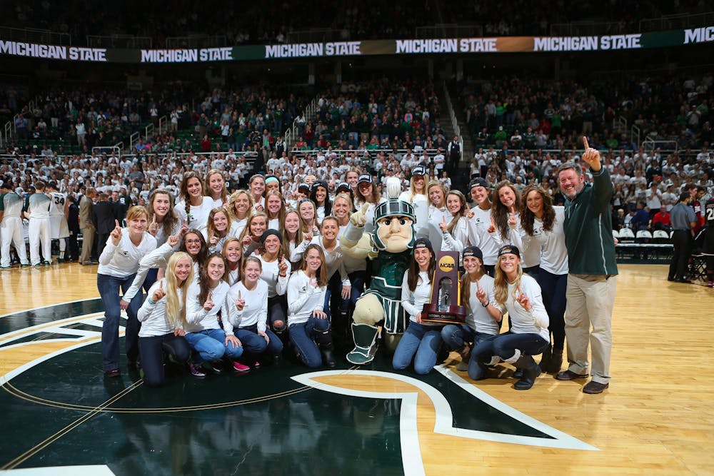 The 2014 NCAA Champion women's cross country team is honored at the Breslin Center. Walt Drenth (pictured right) poses with his team that had a majority of its top runners at the NCAA Championships hail from the state of Michigan.