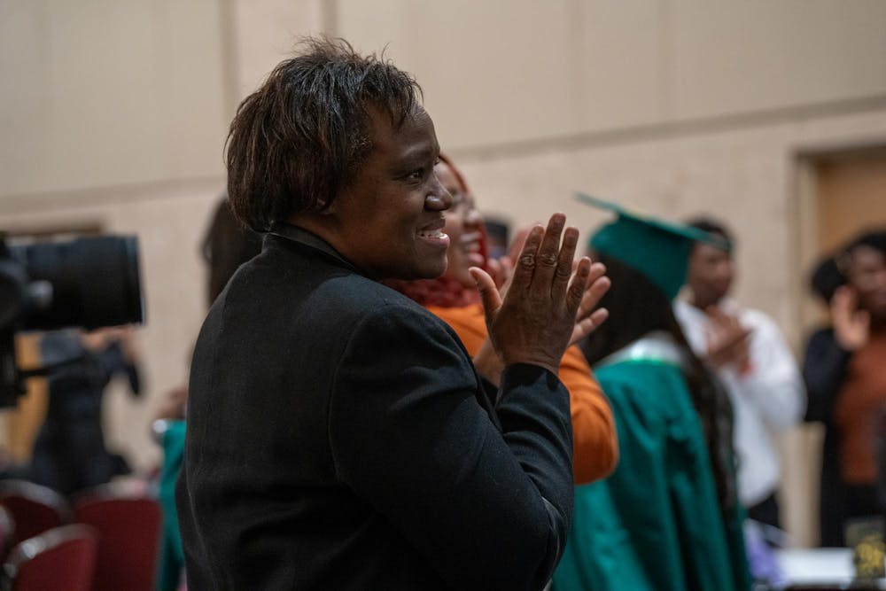 A woman smiles and cheers on the Fall 2023 graduates who walk in the room at the Fall 2023 Black Grad event at the Union Ballroom on Dec. 8, 2023. 