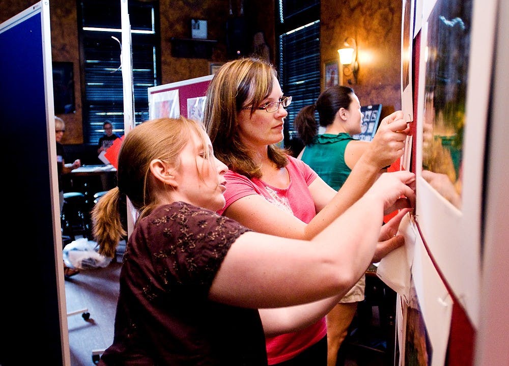 	<p>East Lansing residents Rebecca Roberts, center, and Dorothy Luckie hang artwork June 22, 2011, at Dublin Square Irish Pub in preparation for an art auction held to raise funds for Charlie Waller. Luckie and Roberts were just tow of the dozens of friends and family who volunteered their time to help the Waller family with the fundraiser. Matt Radick/The State News</p>