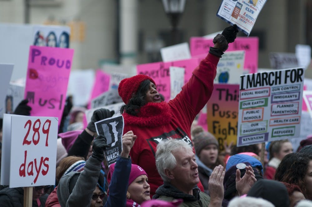 <p>A protestor elevates herself and joins in chant during the Women's March on Jan. 21, 2018, at Michigan State Capitol. Activists listened to speakers and rallied through peaceful protest.&nbsp;</p>