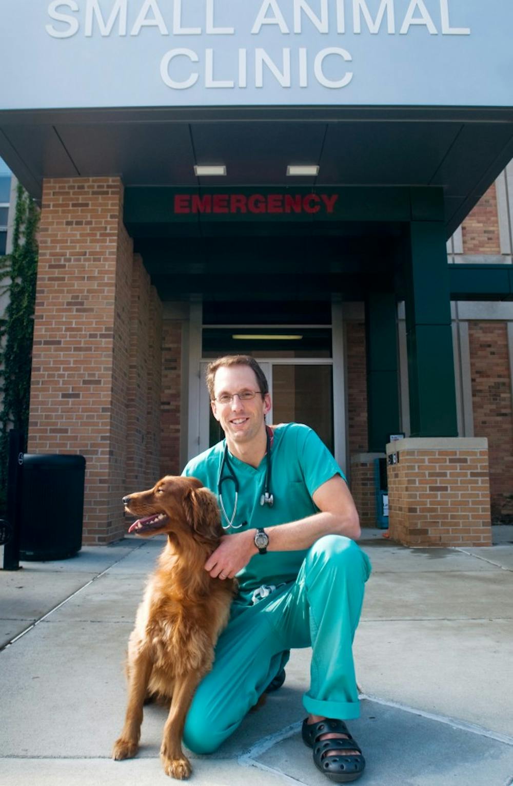 Doctor Matthew Beal kneels with his running companion, Frog, on Wednesday outside the Small Animal Clinic. Beal is an organizer of the IRONDOG Foundation which helps to pay for medical treatment of pets without owners that can afford to pay themselves. Beal said,"we've only helped maybe ten to fifteen animals, but for that one family it makes a difference." Mo Hnatiuk/The State News