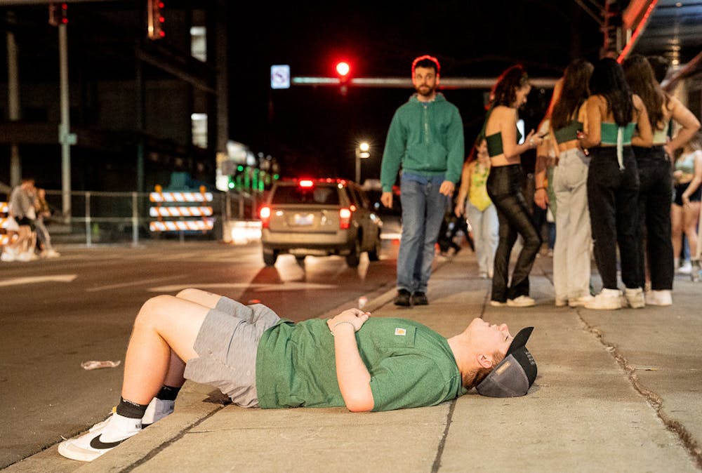 <p>Jagar Rokosz lays on the sidewalk, taking a breather from a day of drinking, on St. Patrick&#x27;s Day, Mar. 17, 2022.</p>