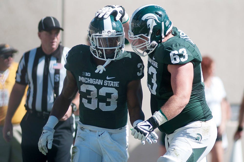 <p>Senior running back Jeremy Langford, 33, celebrates his touchdown with senior offensive lineman Travis Jackson, 63, during the game against Wyoming on Sept. 27, 2014, at Spartan Stadium. The Spartans defeated the Cowboys, 56-14. Raymond Williams/The State News</p>