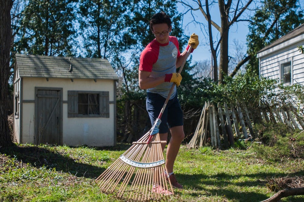 Marketing freshman Silas Olson rakes dead twigs on April 17, 2016 at 1412 N. Harrison Road in East Lansing. "Rent a Rower" is a community outreach program put on by MSU Crew. 
