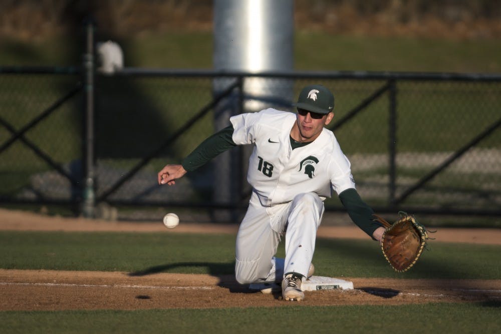 Junior infielder Justin Antoncic (18) goes to catch the ball at first base during the baseball game against Oakland University at McLane Baseball Stadium on April 23, 2019. (Nic Antaya/The State News)