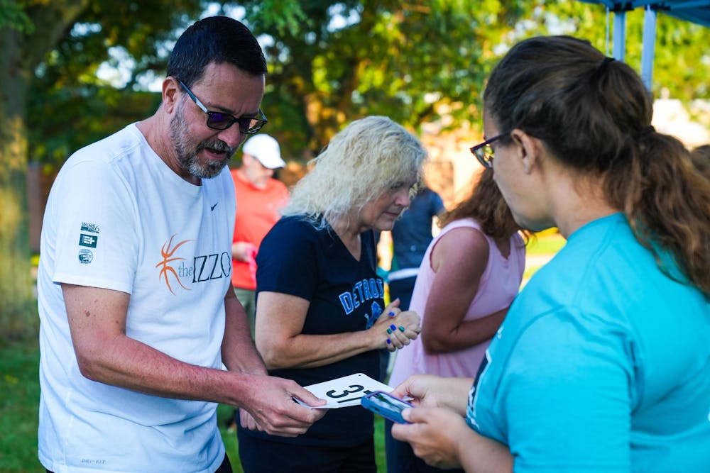 A participant collects their number at a check-in tent during the Big Babies 5k Run at Conrad Hall on Sep. 15, 2024.