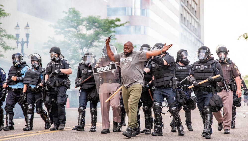 A man is pushed by police through clouds of tear gas in Lansing May 31, 2020 at the riot over the police killing of George Floyd.