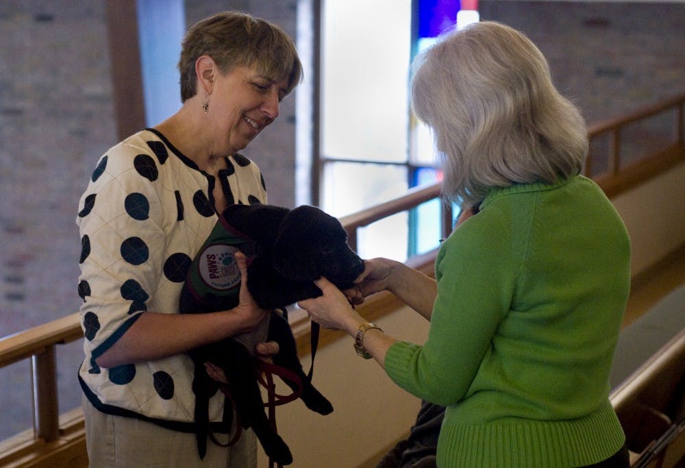 Okemos resident Karen Harsh introduces herself to Bess Sunday at University United Methodist Church, 1120 S. Harrison Road. Socialization is a key part of training the dogs, so McEllhiney-Luster regularly brings her dog to church with her to see people and be in different settings. Matt Radick/The State News