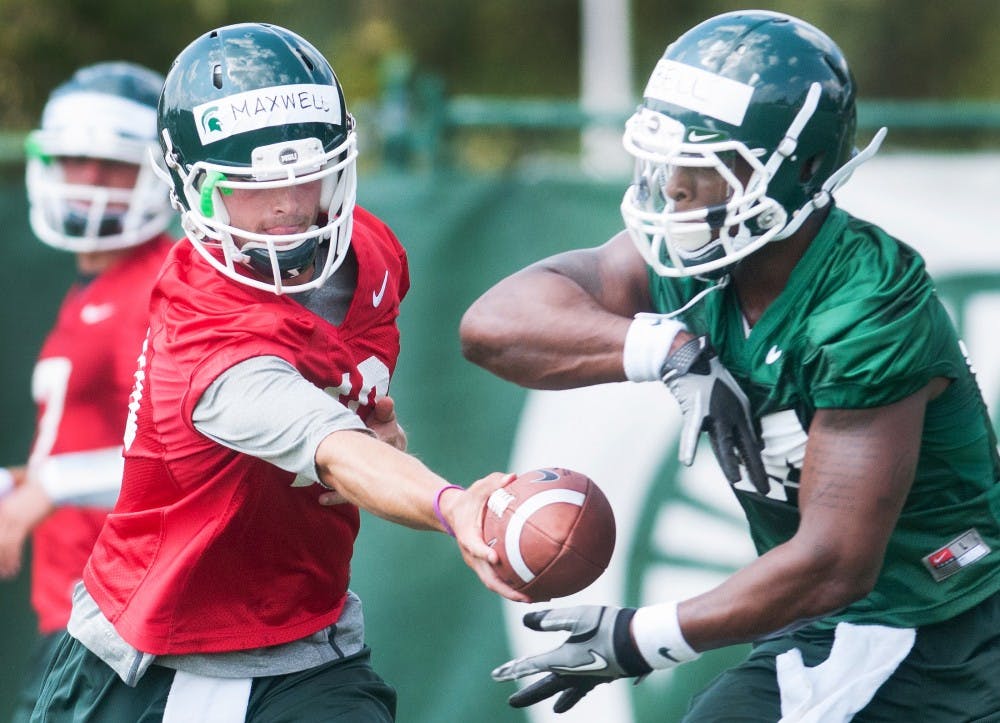 Junior quarterback Andrew Maxwell, left, hands a ball to junior runningback Le'Veon Bell on Saturday, Aug. 4, 2012 at the practice field outside Duffy Daugherty Football Building during football practice. Justin Wan/The State News