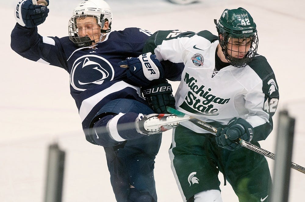 	<p>Junior defenseman Jake Chelios pushes Penn State senior Dominic Morrone out of the way Jan. 26, 2013, at Munn Ice Arena. The Spartans lost, 3-2. Julia Nagy/The State News</p>
