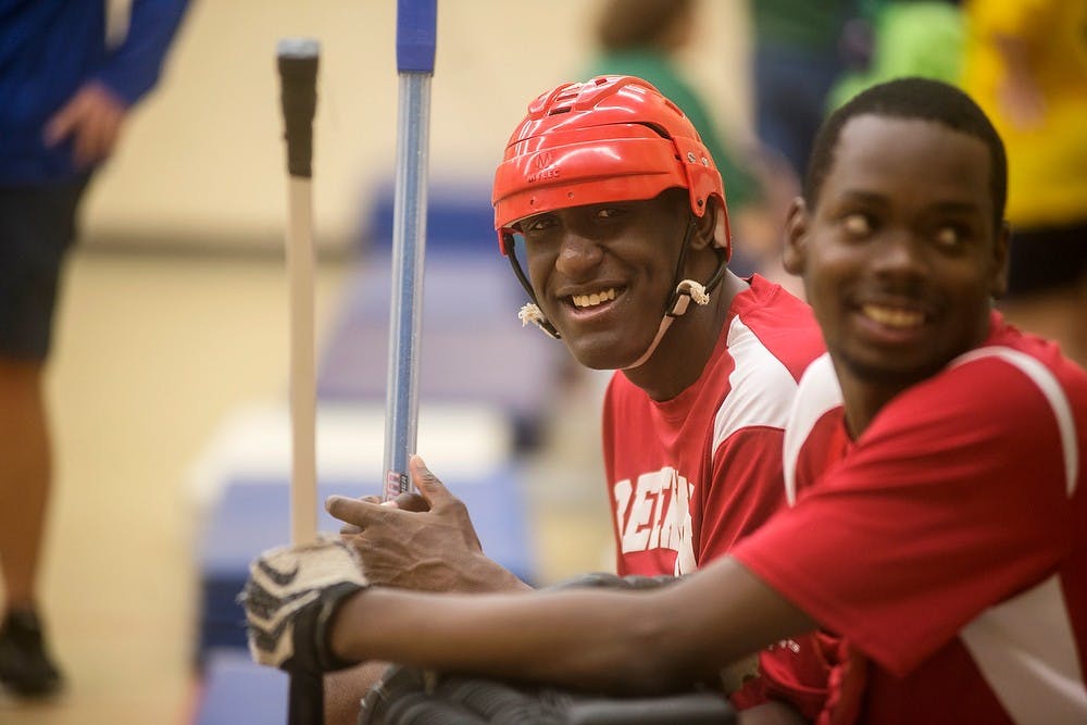 <p>Lansing resident Devante Mugashe, left, watches his teammates play with Lansing resident Nick Hilton on Oct. 29, 2014, during a poly hockey game at Beekman Center, 2901 Wabash Road, in Lansing. The Pi Kappa Alpha fraternity played with the students and were referees in the tournament. Beekman Center is a part of Lansing Schools and provides educational opportunities to students from ages 3-26 years old with physical and cognitive needs. Erin Hampton/The State News</p>