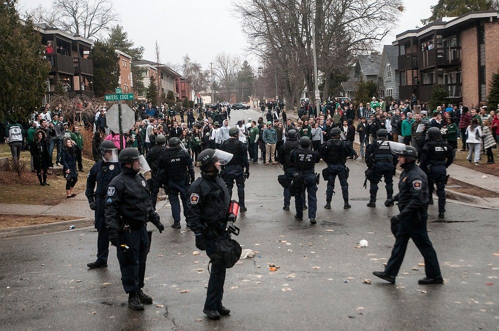 <p>Police officers keep students back from burning backpack March 29, 2015, at Cedar Village Apartments. Students were celebrating the Spartan victory over Louisville in the streets. The State News.</p>