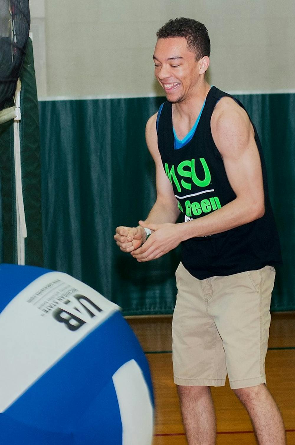 <p>Biochemistry freshman Daniel Jennings laughs while playing volleyball during UAB's "Sports Night" on April 4, 2014, at IM Sports-East. The first 200 students at the event were given free MSU tank tops. Danyelle Morrow/The State News</p>