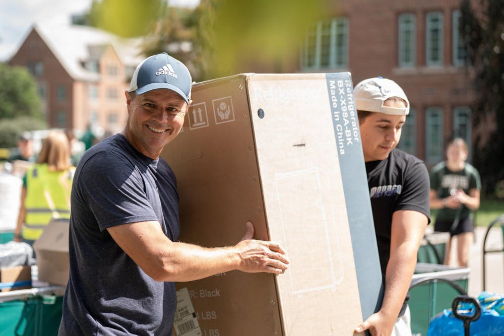 <p>An MSU student carries a large box with a family member during fall move-in at Yakeley Hall in East Lansing, Mich., on Aug. 25, 2026.</p>