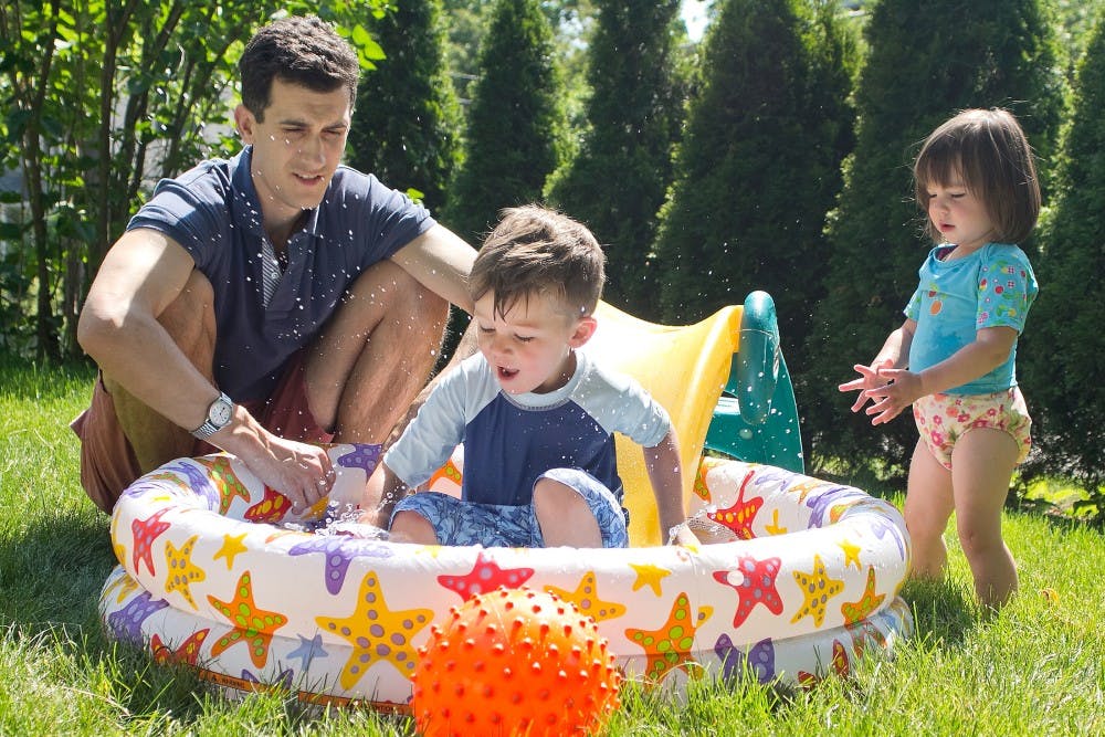 East Lansing resident and father Chris Smith, left, plays outdoors with his children 3-year-old Connor and 1-year-old Cora on Sunday afternoon May 20, 2012. Smith said he and his wife enjoy sitting in the shade while they watch the kids play in the pool. Natalie Kolb/The State News