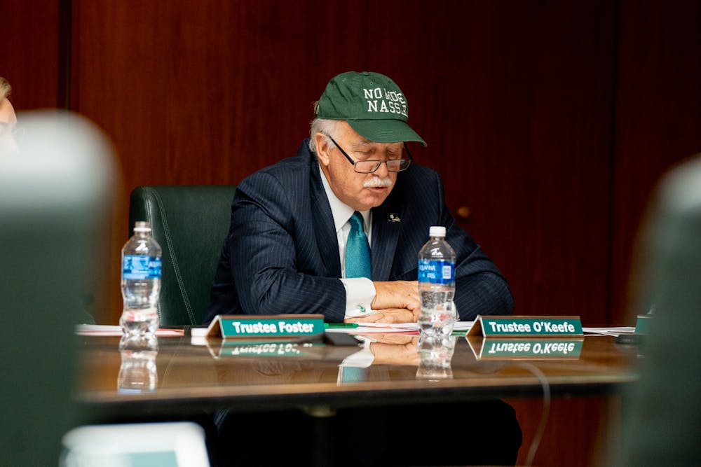 Trustee Pat O'Keefe puts on a "No More Nassar" hat during the Board of Trustees meeting on Oct. 28, 2022.