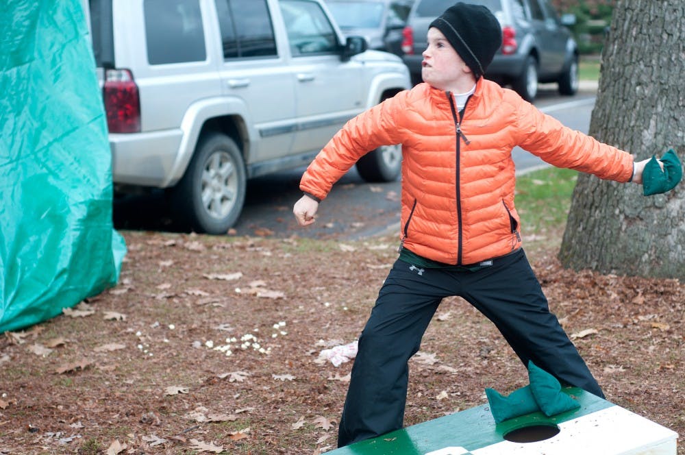 <p>Milford, Mich. resident Brady Collison, 9 plays bean bag toss during tailgating on Nov. 8, 2014 by the Library. Collison said he was excited to attend the Ohio State verse Michigan State game. Jessalyn Tamez/The State News</p>