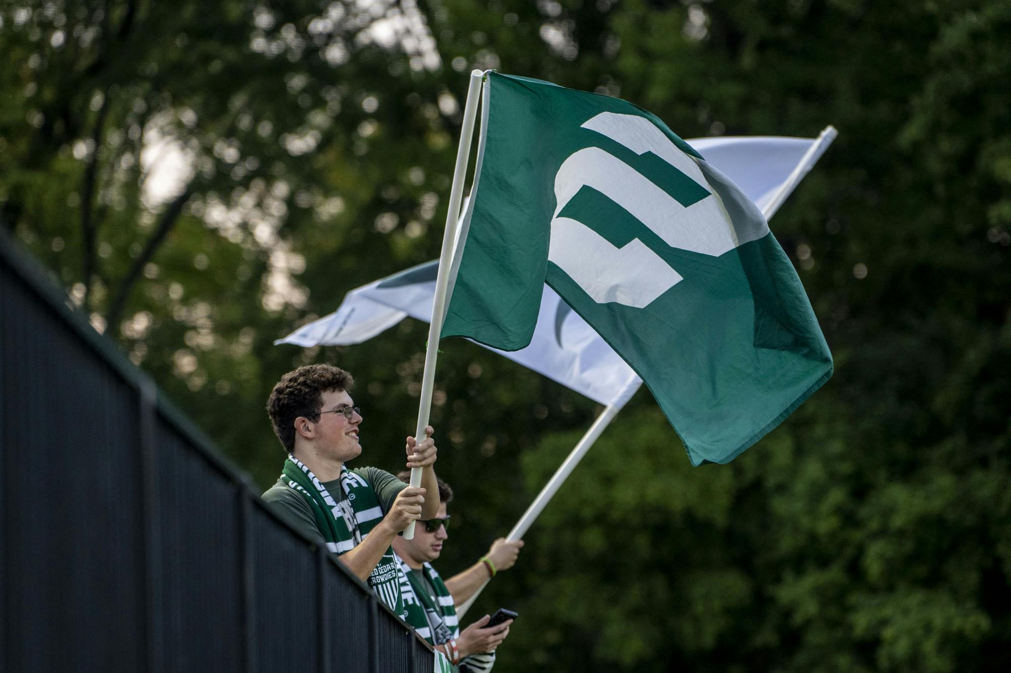 <p>Red Cedar Rowdies wave flags during a MSU and Oakland women’s soccer game at DeMartin Field in East Lansing on Sept. 8, 2022. The Spartans and Grizzlies tied, 0-0.</p>