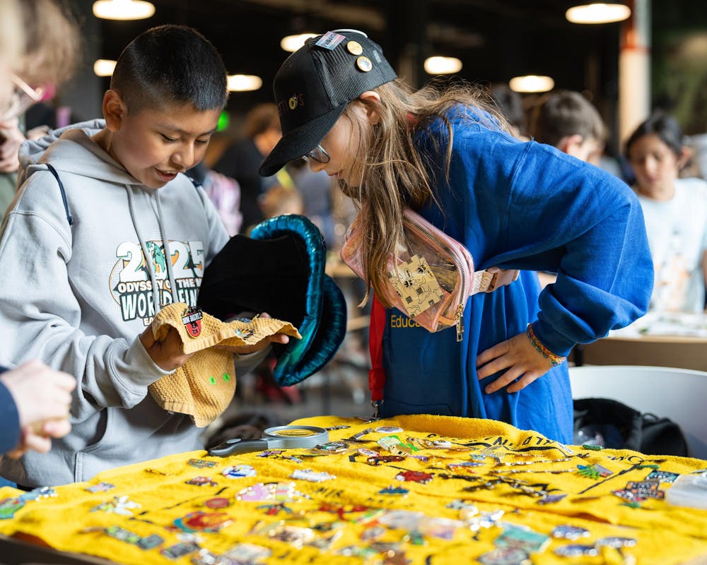 Odyssey of the Minds competitor Sophia interacts with fellow competitors looking to trade pins at the Michigan State STEM Building in East Lansing, Michigan on May 22, 2025. Pin trading is an integral part of OOTM and many stations were setup across campus to enable trades. 