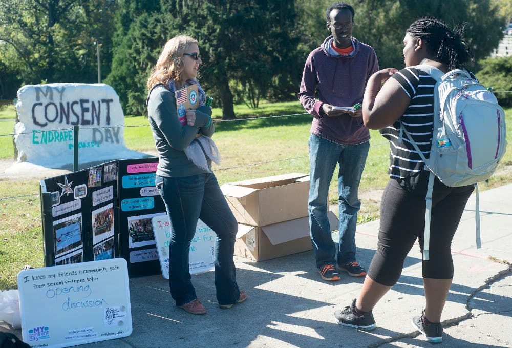 <p>Communication junior Lindsey Wyble, left, and neuroscience senior Olivier Kayiranga talk with no preference freshman Tiara Blair, center, on Sept. 22, 2015 at the rock on Farm Lane. Wyble and Kayiranga are members of the sexual assault crisis intervention team which is a student advocate organization on campus. Alice Kole/The State News</p>
