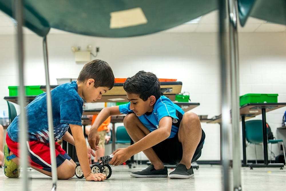 	<p>East Lansing resident Meredith Thompson, 9, left, constructs a robot with Okemos resident Jainil Shah, 10, July 11, 2013, at Natural Resources Building during Robotics &amp; Nano/Bio Technology camp. Participants have the chance to build robots using materials such as Legos. Justin Wan/The State News</p>