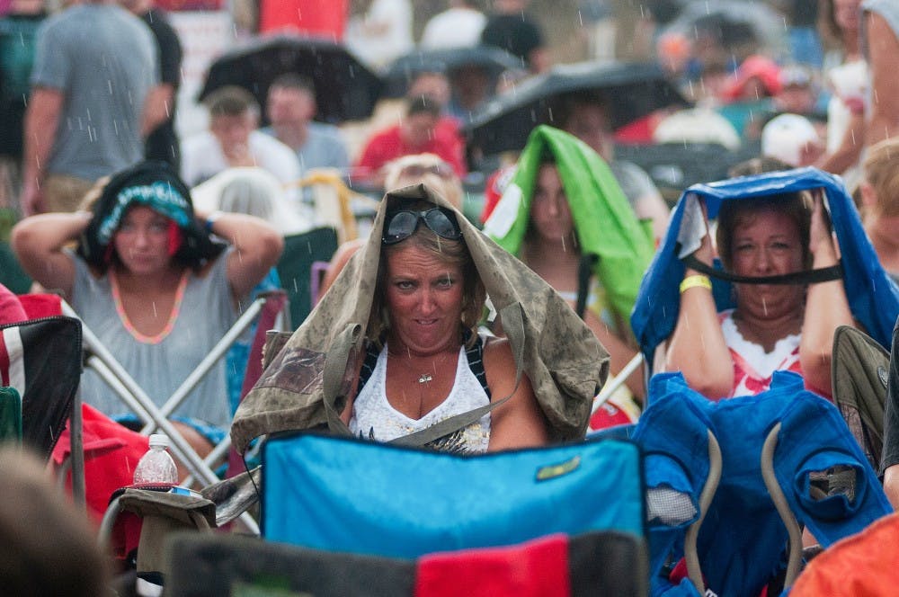 Fans await Three Days Grace's performance in the rain at Common Ground in Lansing’s Adado Riverfront Park on Saturday, July 14, 2012. The show was delayed due to the downpour. Julia Nagy/The State News