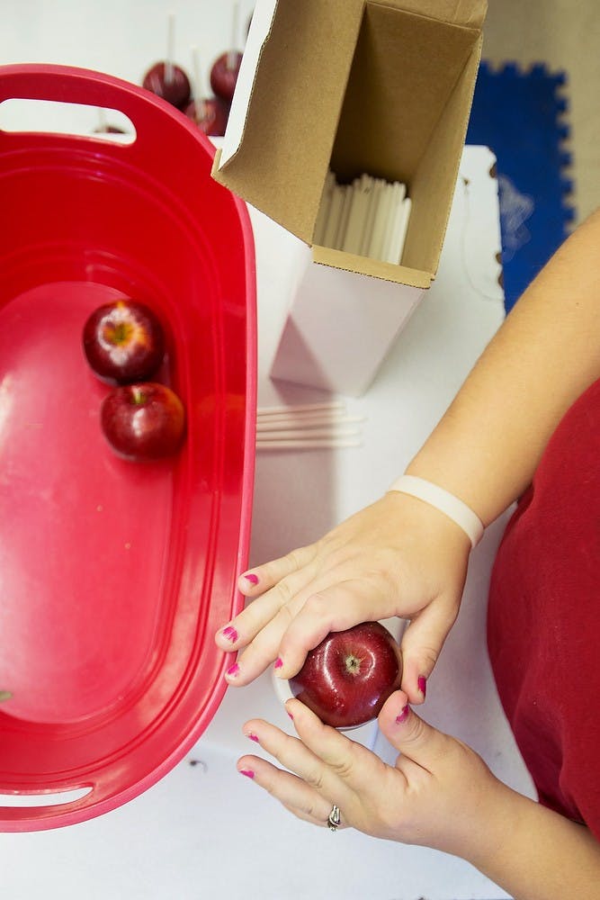 	<p>St. Johns, Mich., resident Brittany Smith spikes apples at Uncle John&#8217;s Cider Mill, 8614 U.S. 127, in St. Johns. Smith was making caramel apples. Julia Nagy/The State News </p>