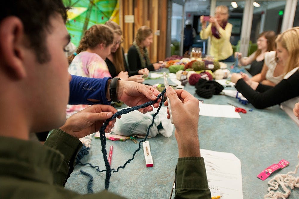 <p>Environmental studies freshman Michael Carroll knits a scarf at the second annual RISE crochet workshop Oct. 3, 2014, at Bailey Hall. Dylan Vowell/The State News</p>