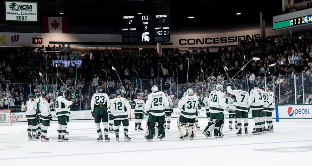 The MSU men's hockey team lift their sticks in the air to celebrate their victory over the University of Michigan at the end of the game at Munn Ice Arena on Dec. 9, 2022. The Spartans defeated the Wolverines 2-1. 