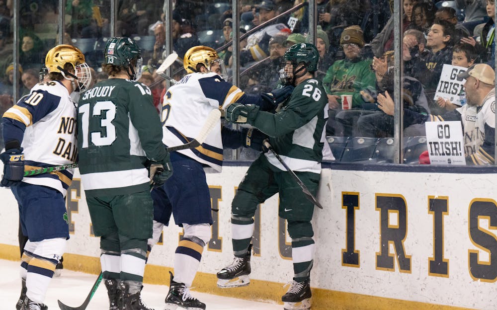 <p>Notre Dame sophomore forward Hunter Strand (left) and MSU freshman forward Tiernan Shoudy look on as Notre Dame's sophomore defenseman Jake Boltmann and MSU's sophomore forward Tanner Kelly get into a scuffle along the boards at Compton Family Ice Arena in Notre Dame, IN on Friday, March 3, 2023. A total of 10 penalty minutes were assessed during the matchup.</p>