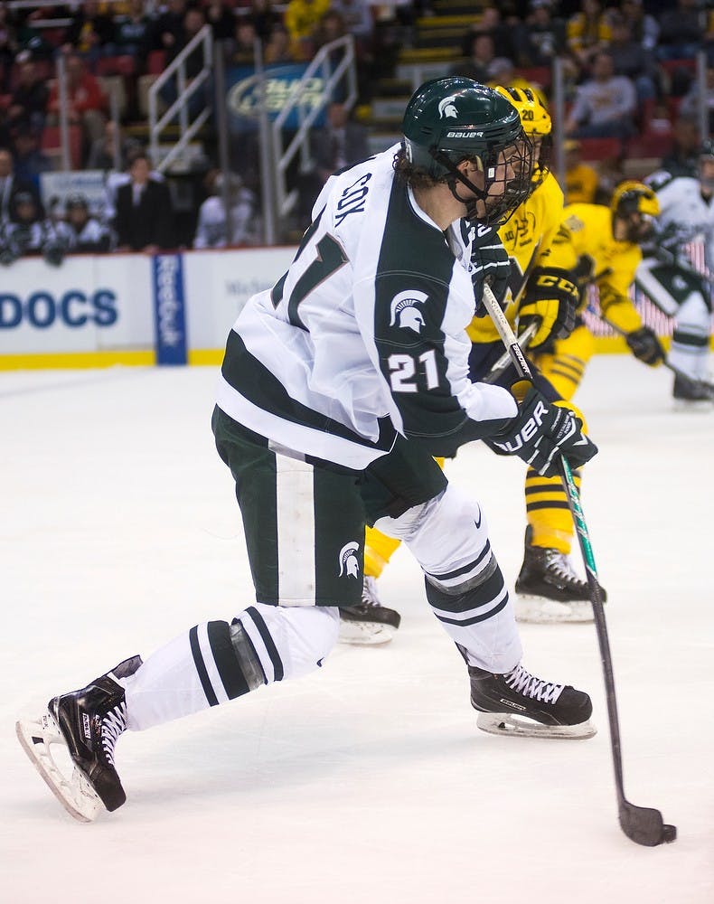 <p>Sophomore forward Joe Cox takes a shot at the Michigan net Dec. 29, 2014, during the 50th Great Lakes Invitational at Joe Louis Arena in Detroit. The Spartans were defeated by the Wolverines, 2-1. Danyelle Morrow/The State News</p>