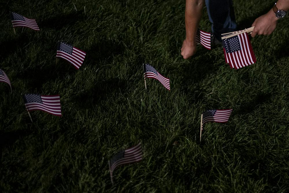Kort Ian, a junior studying agribusiness and a Marine Corps veteran who served seven years, places an American flag in the ground during preparations for a 9/11 memorial at the Rock on Michigan State University’s campus in East Lansing, Mich., Thursday, Sept. 10, 2026. MSU Young Americans for Freedom and MSU College Republicans placed 2,977 flags, one for each victim killed in the Sept. 11, 2001, terrorist attacks.