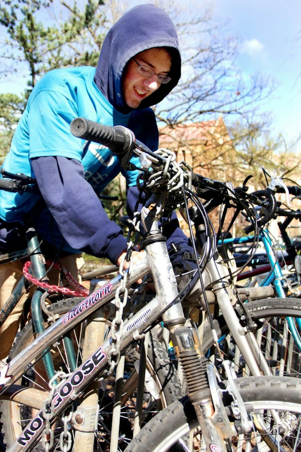 Computer science junior Raymond Heldt locks up his bike Thursday afternoon outside of the Main Library. One of RHA?s committees is doing a bike census where it will look at the number of registered bikes on campus, how many there are at bike racks, and how crowded it is in general to see if there?s a better way to store bikes around campus. Aaron Snyder/The State News.