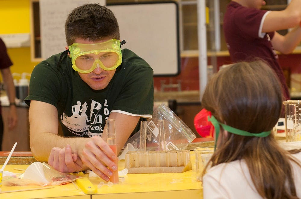 	<p>Graduate student James Poteracki shows Bloomfield Hills resident Kaelin McNulty, 5, strawberry <span class="caps">DNA</span> Nov. 9, 2013, at Impression 5 Science Center. A lab was held to teach kids how to extract <span class="caps">DNA</span> from strawberries. Margaux Forster/The State News</p>