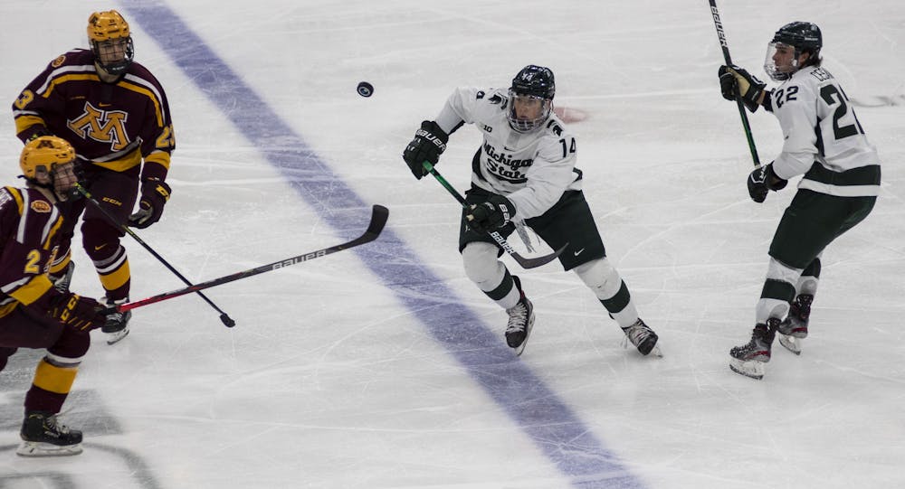 Junior forward Adam Goodsir (14) charges at the puck while still midair in the third period. The Spartans fell to the Golden Gophers, 3-1, on Dec. 3, 2020.