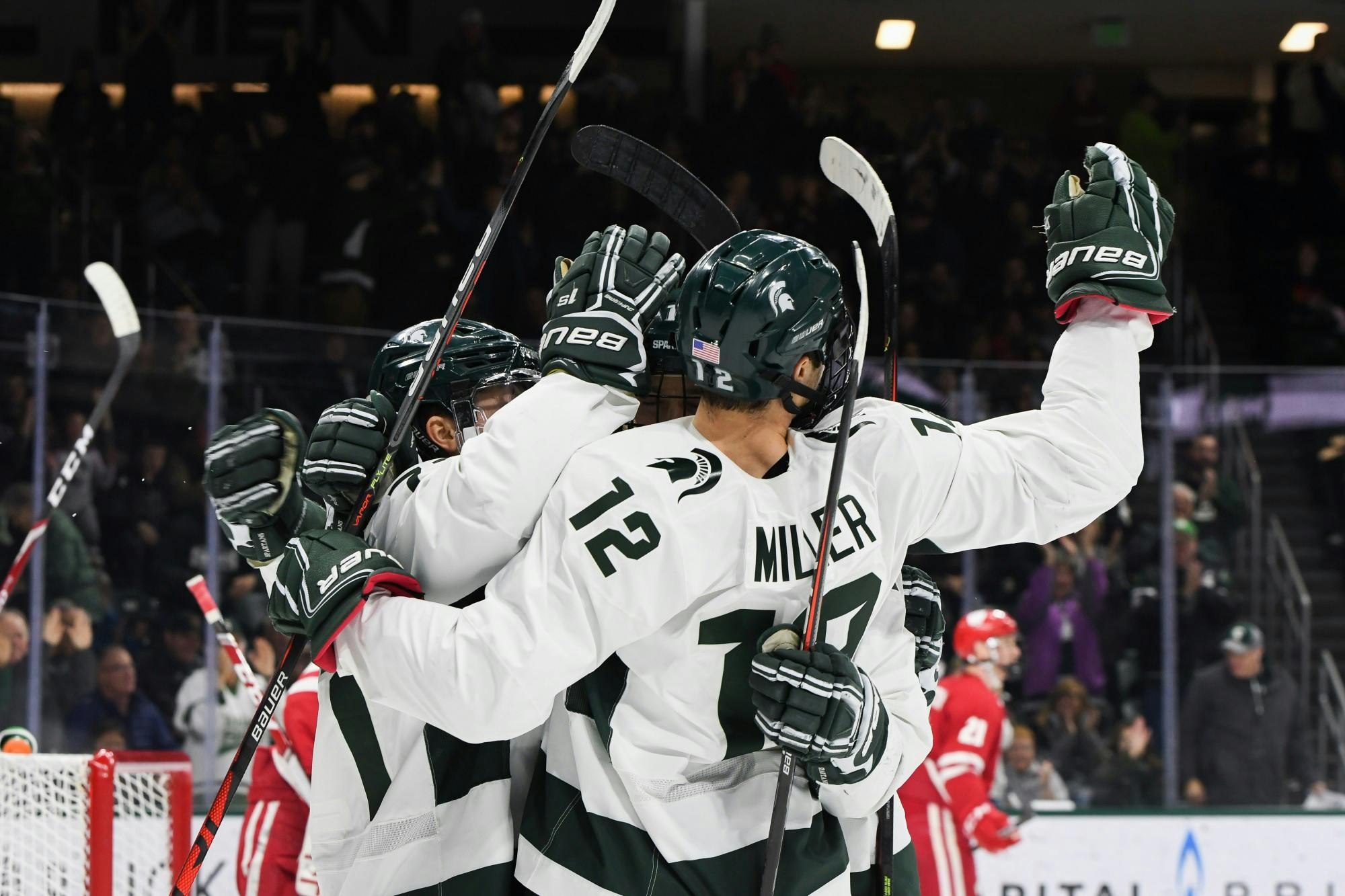 Players celebrate a goal by forward Tommy Miller (12) during the game against Wisconsin at the Munn Ice Arena on December 6, 2019. The Spartans defeated the Badgers 3-0.