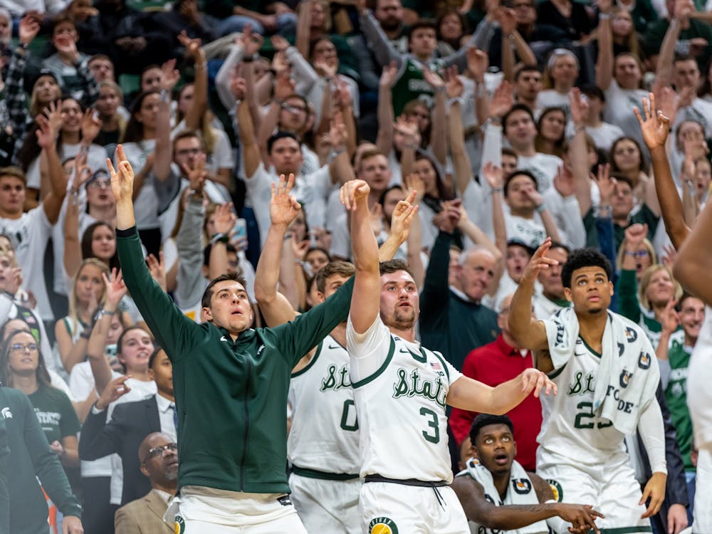 <p>Then-sophomore guard Foster Loyer (3) shoots a three-pointer while then-senior forward Conner George (left), then-freshman forward Malik Hall (right) and the Izzone watch the shot. The Spartans defeated the Wildcats, 79-50, at the Breslin Student Events Center on January 29, 2020.</p>