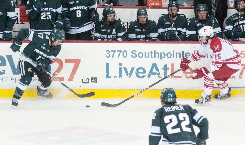 Senior defenseman Matt Crandell and Miami forward Bryon Paulazzo go after the puck during the Spartan hockey game vs. Miami University Saturday night at Steve Cady Arena in Oxford, Ohio. The Miami University Redhawks defeated the Michigan State Spartans 4-1. Derek Berggren/The State News