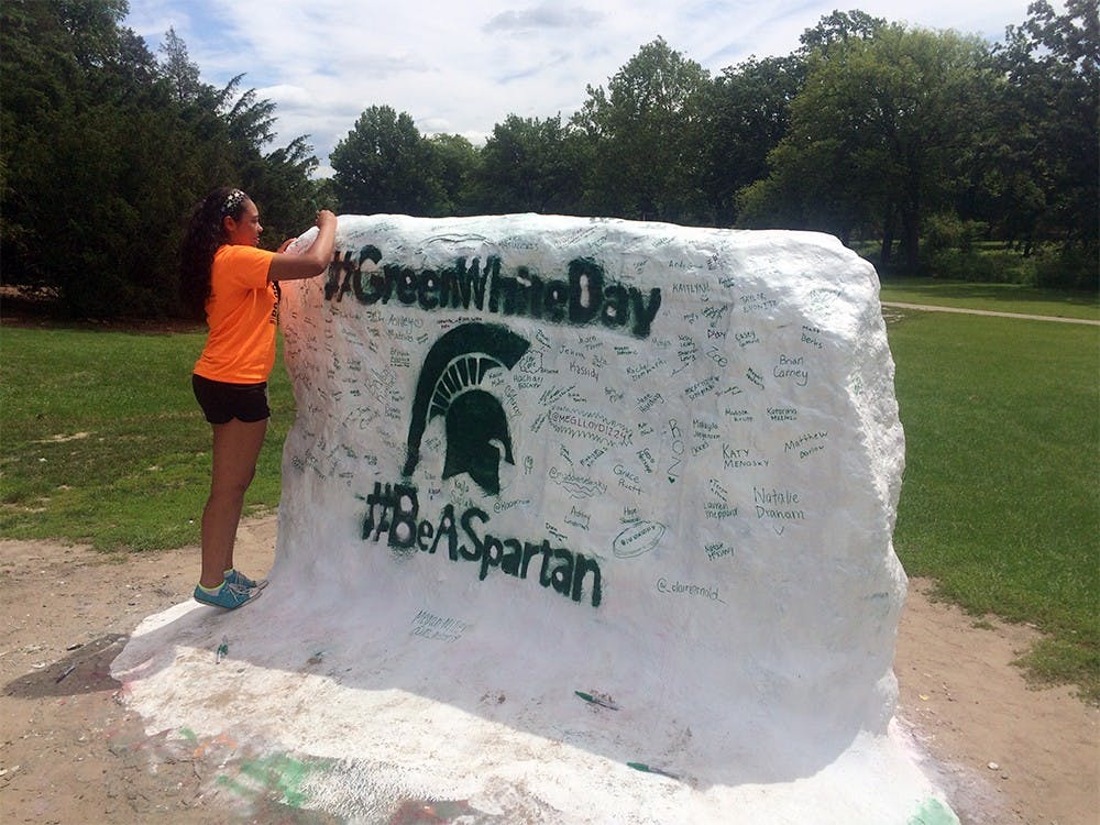 <p>Rachel Moore, a senior at Goodrich High School, signs The Rock at Farm Lane July 22, 2015 during Green and White Day activities. Ryan Kryska/The State News</p>