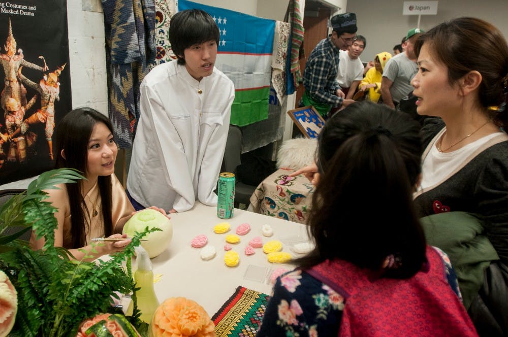 <p>Graduate student Paphajree Vajrapana, left, and supply chain management junior Natchanon Sereeyothin talks about Thailand culture with East Lansing residents Cecilia Yao, age 11, left, and Yao Tong, right, on Nov. 23, 2014, during the Global Fest at the MSU Union.  The Global Festival lets international students from around the world showcase their cultures and home traditions. Raymond Williams/The State News</p>
