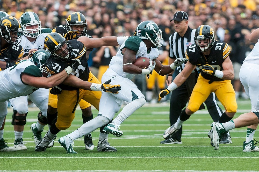 	<p>Junior running back Jeremy Langford slips past the arms of Iowa defensive lineman Carl Davis, Oct. 5, 2013, at Kinnick Stadium. The Spartans defeated the Hawkeyes, 26-14. Khoa Nguyen/The State News</p>