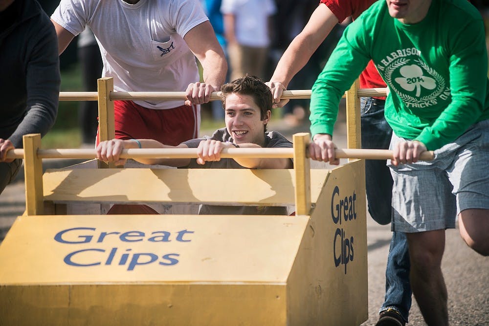 <p>Hospitality business junior Killian McClure sits in a cart as his fraternity brothers push him through the race Oct. 19, 2014, during Lambda Chi Alpha's philanthropy event, Jr. 500 race at East Lansing High School on Burcham Drive. The proceeds of the event are meant for Ele's Place which provides services to children and teens who have lost a parent. Erin Hampton/The State News</p>
