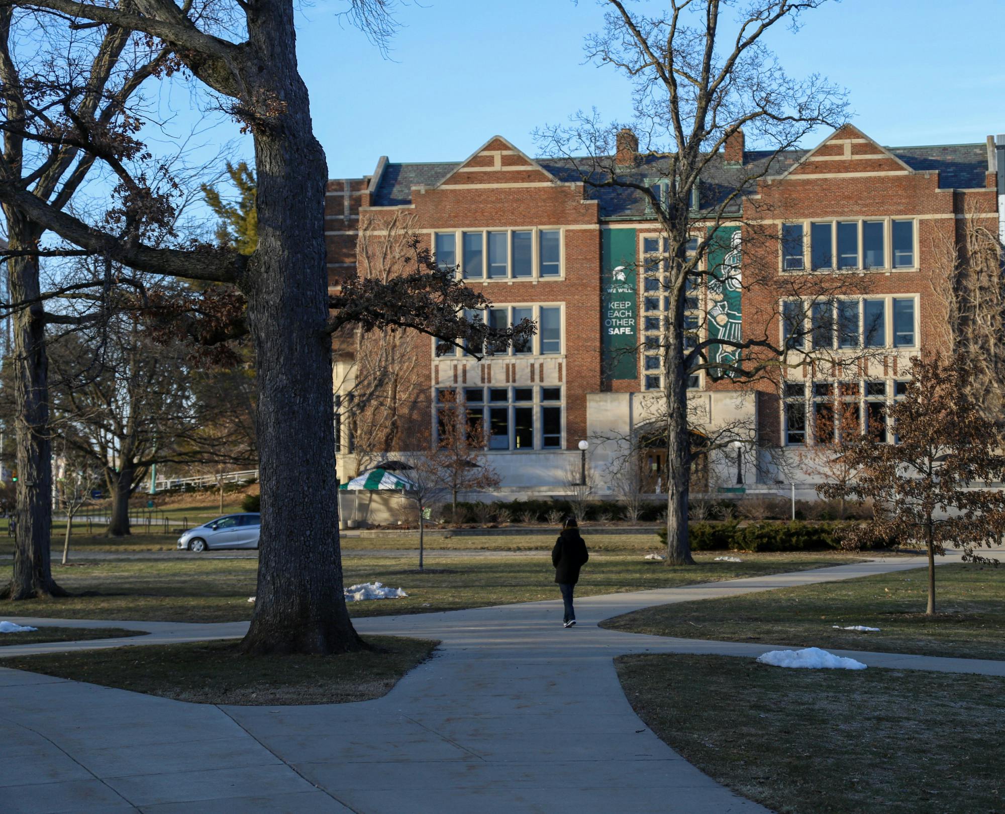 <p>The MSU Union has a large sign that says, &quot;Keep Each Other Safe,&quot; and below the sign is a person walking on campus on March 7, 2021. </p>