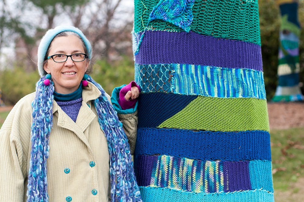 Lansing resident, Lynn Hershberger, lead coordinator for the yarn bombing project stands next to a trees with the art on Monday, Oct. 29, 2012, at the 4-H Children's Garden. The garden was vandalized over the weekend but was repaired later that same day. Adam Toolin/The State News