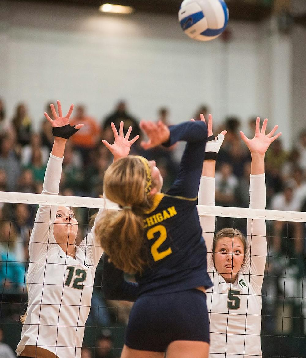 <p>Freshman setter Rachel Minarick and redshirt freshman middle blocker Megan Tompkins attempt to block Michigan  defensive specialist Caroline Knop Oct. 3, 2014, during a game against the University of Michigan at Jenison Fieldhouse. The Spartans defeated the Wolverines, 3-1. Erin Hampton/The State News</p>