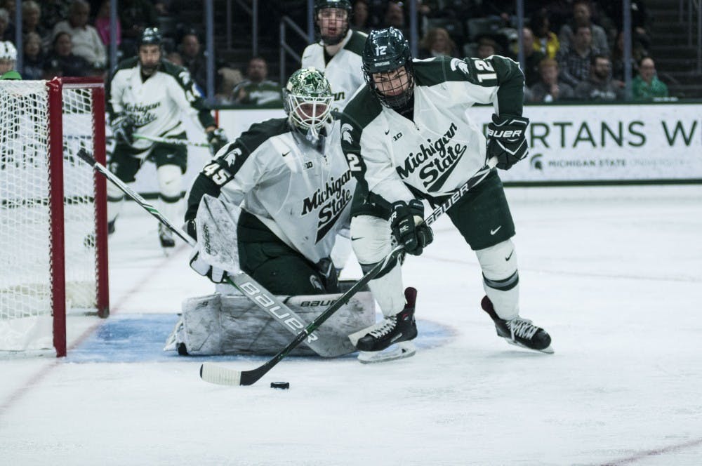 Freshman Defenseman Tommy Miller (12) looks to clear the puck from his zone during the game on Feb. 17, 2018 at Munn Ice Arena. The Spartans trailed the Nittany Lions 3-1 after the second period. (C.J. Weiss | The State News)