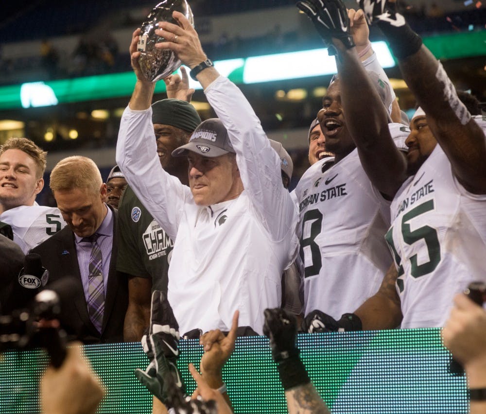 Head coach Mark Dantonio holds up the Big Ten championship trophy on Dec. 5, 2015 at the Big Ten championship game against Iowa at Lucas Oil Stadium in Indianapolis. The Spartans defeated the Hawkeyes 16-13. 