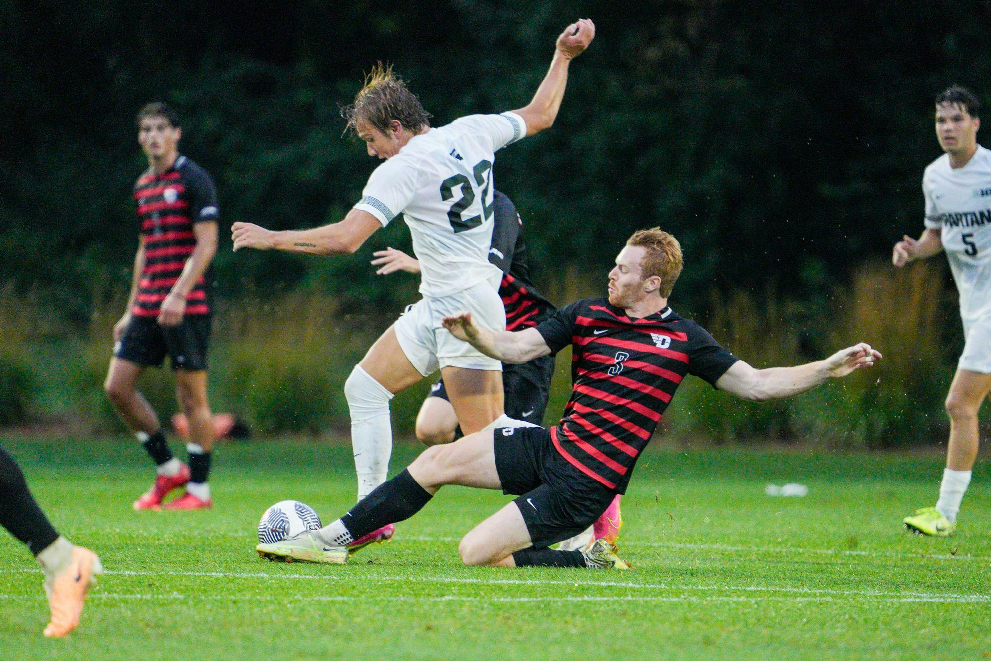 <p>Sophomore forward Jake Spadafora #22 is tackled by a University of Dayton player during a game at DeMartin Soccer Complex on Sept. 7, 2023.</p>