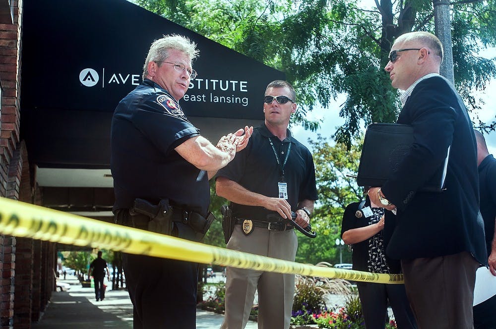 	<p>East Lansing police talk with bystanders Tuesday, Aug. 14, 2012, outside the Douglas J Aveda Institute, 331 East Grand River Avenue. Budget cuts have reduced police staffs across Michigan. State News File Photo</p>